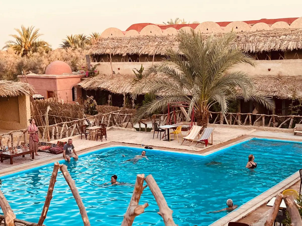 The Aghurmi courtyard with palms, thatched huts and the pool